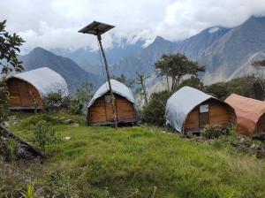 a group of huts on a hill with mountains in the background at Machupicchu EcoLodge in Cusco