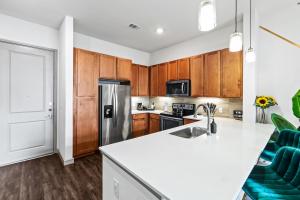 a kitchen with wooden cabinets and a stainless steel refrigerator at Luxury Apartment with KING BED and POOL and FREE PARKING 4 in Houston