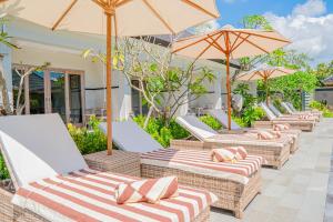 una fila di sedie a sdraio con ombrelloni su un patio di Green D'Mel Luxury Homestay a Nusa Dua