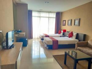 チェンマイにあるザ グランド ヴィパナン レジデンスのベッド2台とソファが備わるホテルルームです。