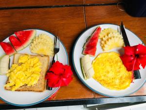 two plates of food with eggs and fruit on them at Rumah Kundun in Gili Trawangan