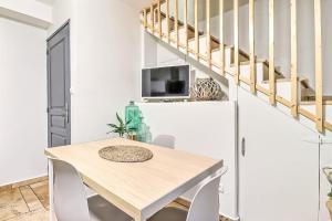a dining room with a table and a tv and stairs at LA MAISON FAYARD - 3 pers - Centre Clim Wifi Cosy Garage in Saint-Gilles