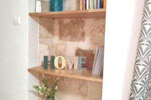 a shelf with the word home written on it at LA MAISON FAYARD - 3 pers - Centre Clim Wifi Cosy Garage in Saint-Gilles