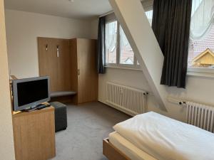 a bedroom with a bed and a tv and a staircase at Hotel Bären in Villingen-Schwenningen