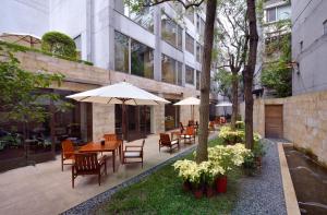 un patio esterno con tavoli, sedie e ombrelloni di les suites taipei ching cheng a Taipei