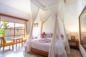 a bedroom with a bed with mosquito nets at Alam Puisi Villa Ubud in Ubud