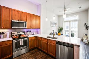 una cocina con armarios de madera y electrodomésticos de acero inoxidable en Downtown Houston Condo w Pool and Free Parking 6 en Houston
