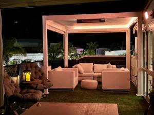 a screened in porch with couches and chairs at night at Laneway Apartments in Napier