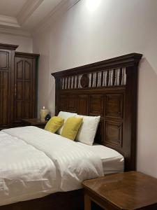 a bed with a wooden headboard and two yellow pillows at درة العروس - فيلا الحلم Dream 4u in Durat Alarous