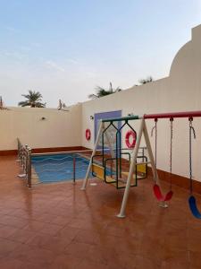 a playground with a slide and swings at درة العروس - فيلا الحلم Dream 4u in Durat Alarous