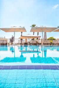 een zwembad met tafels en parasols bij The Scots Hotel in Tiberias