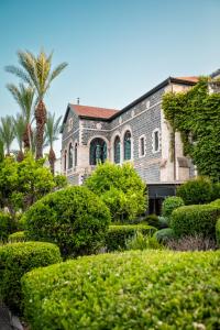 a building with trees and bushes in front of it at The Scots Hotel in Tiberias