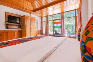 a bedroom with a bed and a large window at FabHotel Hira Invitation in Manāli
