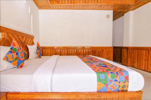 a bedroom with a large white bed with colorful pillows at FabHotel Hira Invitation in Manāli