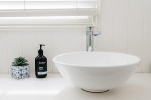 a white bathroom with a white sink and a window at Anchor Geelong in Geelong