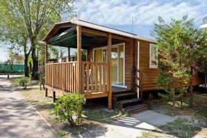 a small wooden cabin with a porch and stairs at Camping Grande Italia Vulcano 7 in Chioggia