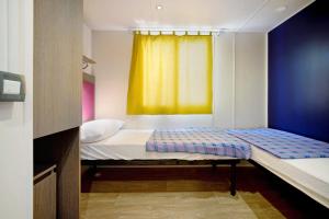 ein kleines Bett in einem Zimmer mit gelbem Fenster in der Unterkunft Camping Grande Italia Vulcano 8 in Chioggia
