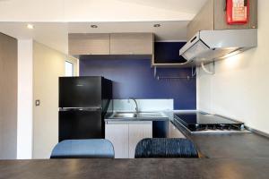 eine Küche mit einem schwarzen Kühlschrank und 2 blauen Stühlen in der Unterkunft Camping Grande Italia Vulcano 8 in Chioggia