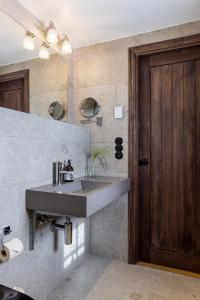 a bathroom with a sink and a wooden door at Ekenäs Gård på Österlen in Kivik