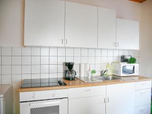 La cuisine est équipée de placards blancs, d'un évier et d'un four micro-ondes. dans l'établissement SUNNYHOME Monteurwohnungen und Apartments in Weiden, à Moosbürg