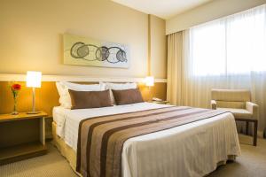 a hotel room with a large bed and a chair at Astron Hotel Bauru by Nobile in Bauru