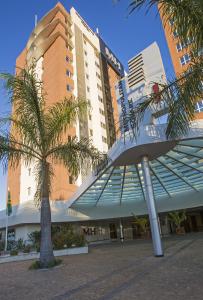 a building with a palm tree in front of it at Astron Hotel Bauru by Nobile in Bauru