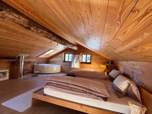 a large bed in a room with a wooden ceiling at Chalet Biene - Swiss Alp Chalet with Sauna and Jacuzzi in Ulrichen