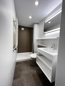 a white bathroom with a toilet and a sink at Hotel Arlenwald in Arosa