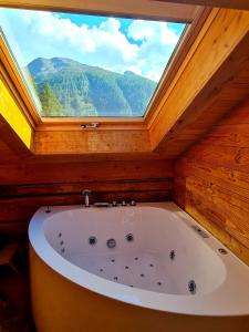 a large bath tub in a room with a window at Chalet Biene - Swiss Alp Chalet with Sauna and Jacuzzi in Ulrichen