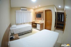 a hotel room with two beds and a desk at Hotel Portal da Amazônia in Várzea Grande