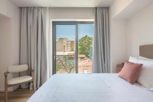 - une chambre avec un lit blanc et une fenêtre dans l'établissement Ceramian Athens, à Athènes