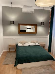 a bedroom with a green bed and a mirror at Apartamenty Żeglarska 25 in Toruń