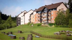 un grand bâtiment au sommet d'une colline herbeuse dans l'établissement Terme Olimia - Aparthotel Rosa, à Podčetrtek