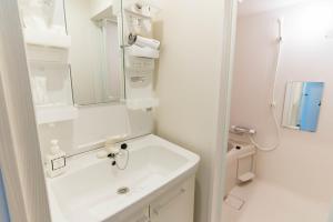 W białej łazience znajduje się umywalka i lustro. w obiekcie Bijou Suites Sorriso - Vacation STAY 82795 w Osace