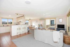 a living room with a white couch and a kitchen at Esplanade Escape Absolute Beachfront WIFI-NBN in Middleton