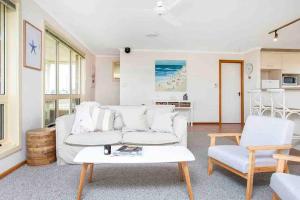 a living room with a white couch and a table at Esplanade Escape Absolute Beachfront WIFI-NBN in Middleton