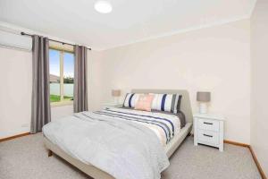 a white bedroom with a bed and a window at Esplanade Escape Absolute Beachfront WIFI-NBN in Middleton