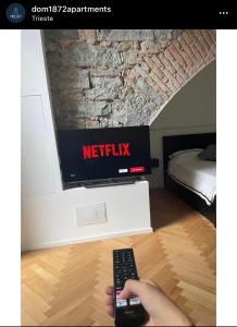a person holding a remote control in front of a television at DOM1872 apartments in Trieste