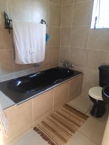 a bathroom with a black bath tub and a toilet at Cottage @19th in Pretoria