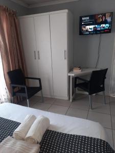 比勒陀利亚Cottage @19th的一间卧室，里面有一张床、一张桌子和一台电视。