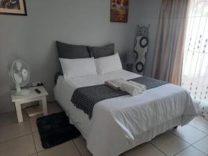 een slaapkamer met een groot bed met witte lakens bij Cottage @19th in Pretoria