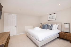 a white bedroom with a white bed and a wooden dresser at JOIVY Stylish flat near Perth Museum in Perth