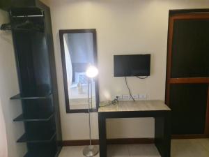 a room with a desk with a mirror and a television at Coron town travellers inn in Coron