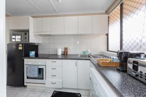 a kitchen with white cabinets and a black refrigerator at Tuggeranong Short Stay #11 in Tuggeranong