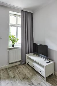 ein Wohnzimmer mit einem TV auf einer weißen Kommode in der Unterkunft Niebieski Apartament DE LUX dla 4 osób Chorzów Katowice in Chorzów
