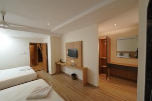 a hotel room with two beds and a television at Southern Residency in Cochin