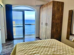 Oyster Flats - Seaside Apartment 7 في Żebbuġ: غرفة نوم بسرير ونافذة كبيرة