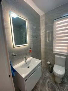 a bathroom with a sink and a toilet and a mirror at Oyster Flats - Seaside Apartment 7 in Żebbuġ