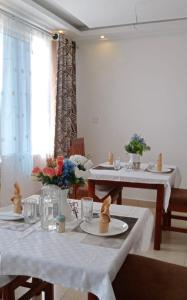 un comedor con 2 mesas con mantel blanco en Hellenis Guest House, en Kakamega