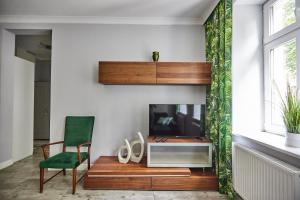 un salon avec une télévision et une chaise verte dans l'établissement Zielony Apartament DE LUX dla 4 osób Chorzów Katowice, à Chorzów